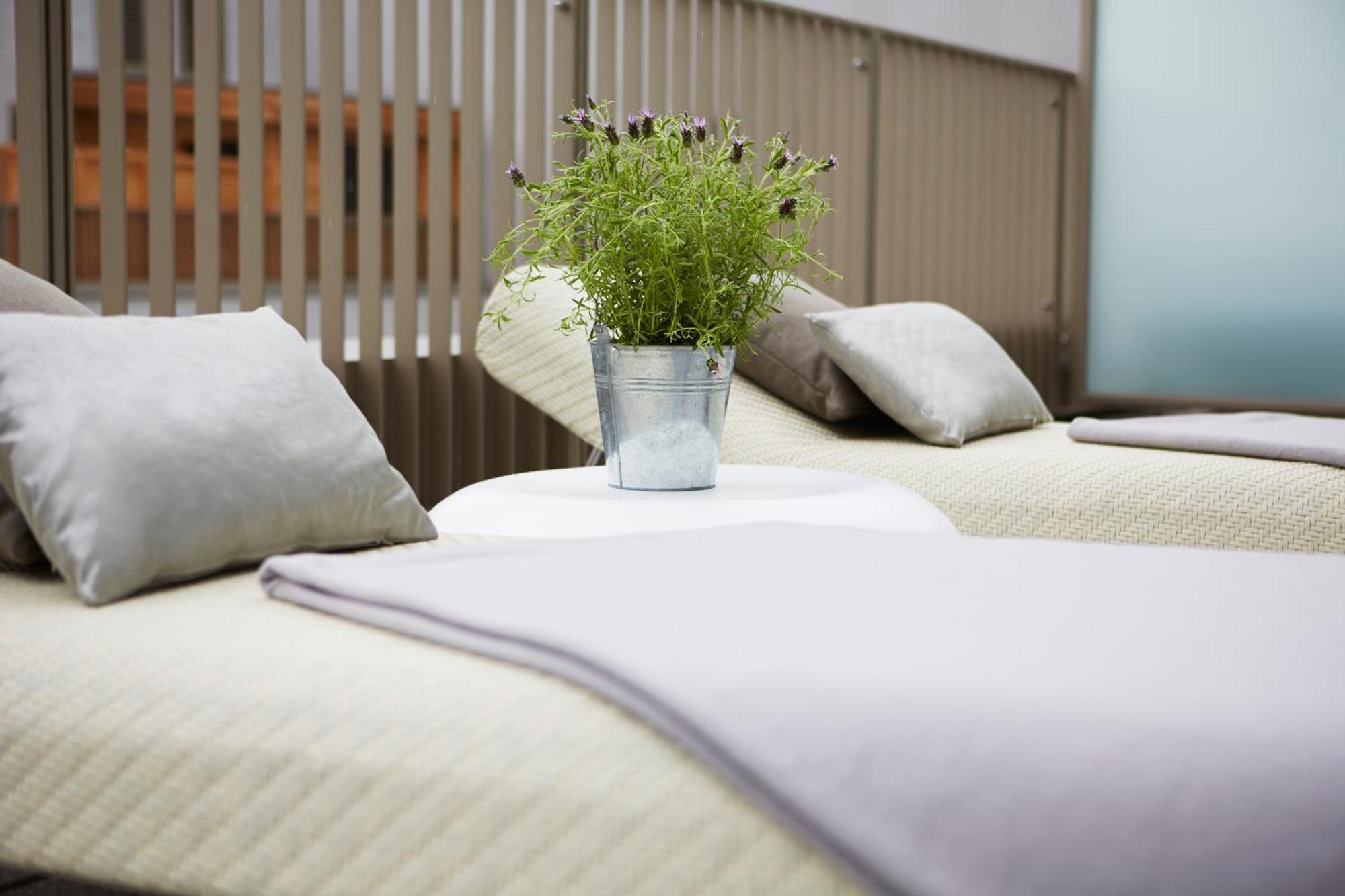 Steigenberger Hotel Am Kanzleramt Берлін Номер фото The photo shows two lounge chairs with soft, light-colored cushions. Between them, there is a small round table featuring a metal bucket filled with greenery. The setting appears to be designed for relaxation, with a clean and modern aesthetic, likel
